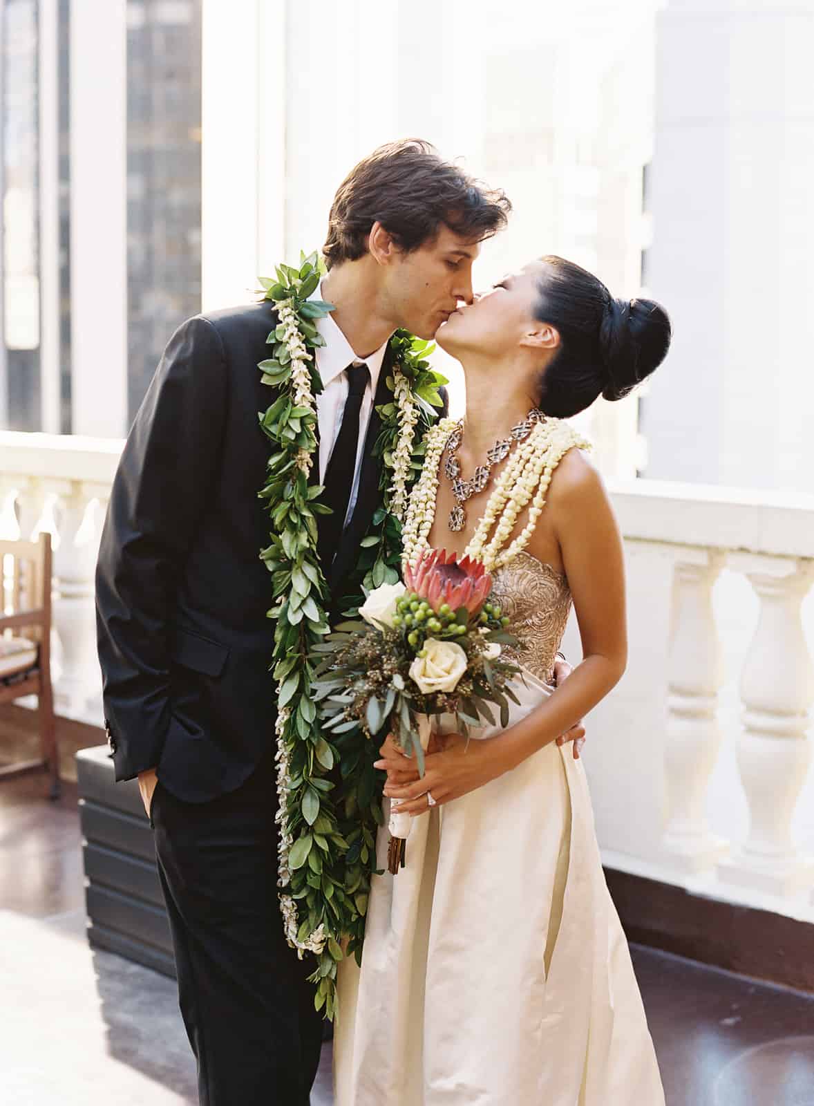 Maile ti leaf and white orchid lei and protea bouquet