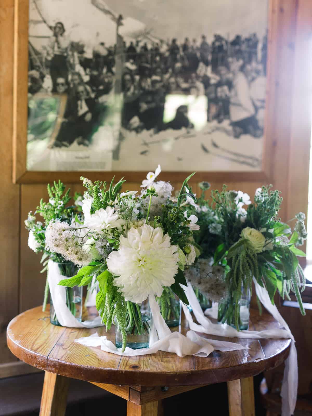 bouquets in vases on wood table with old framed photo