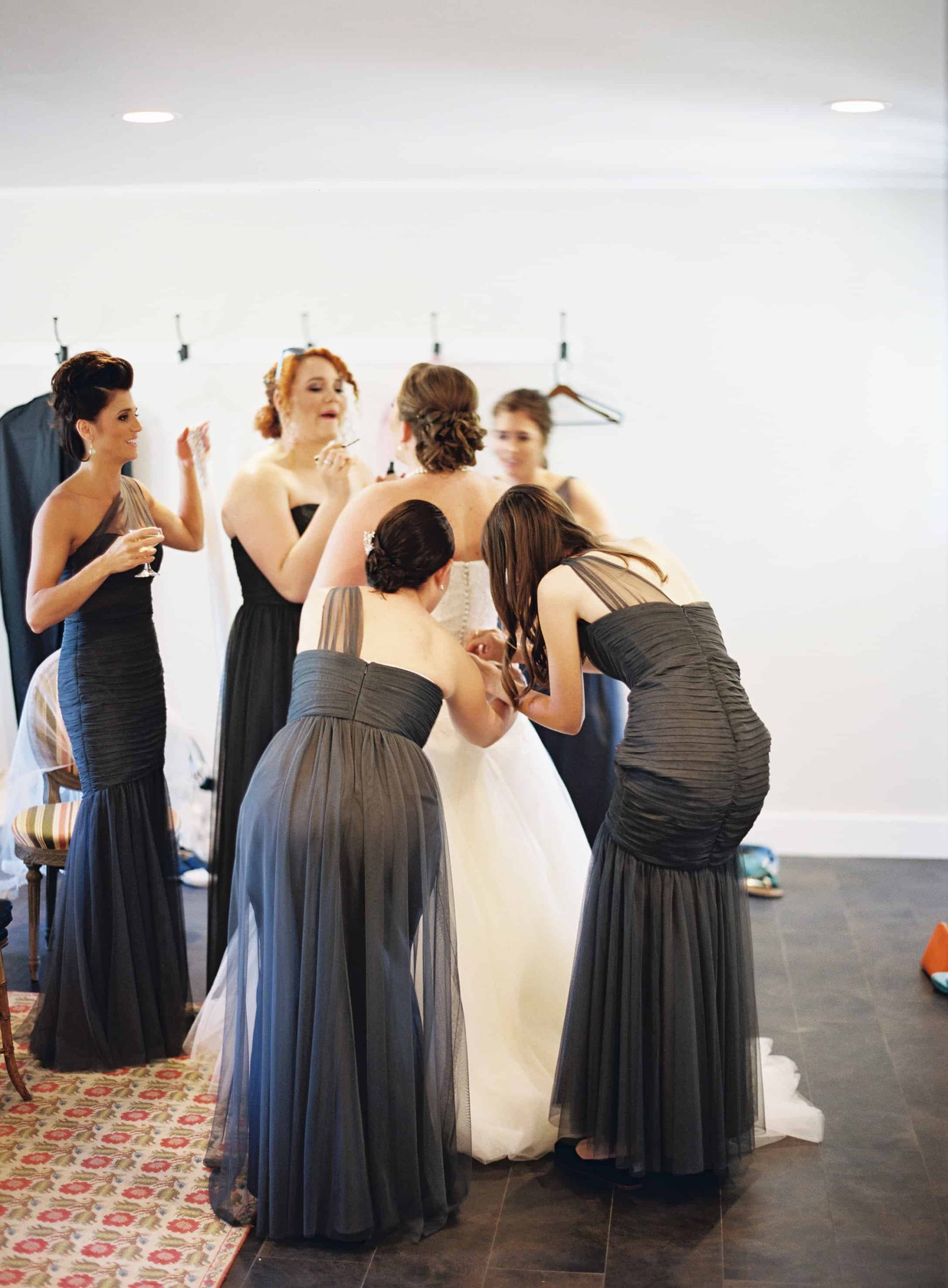bridesmaids getting bride into dress