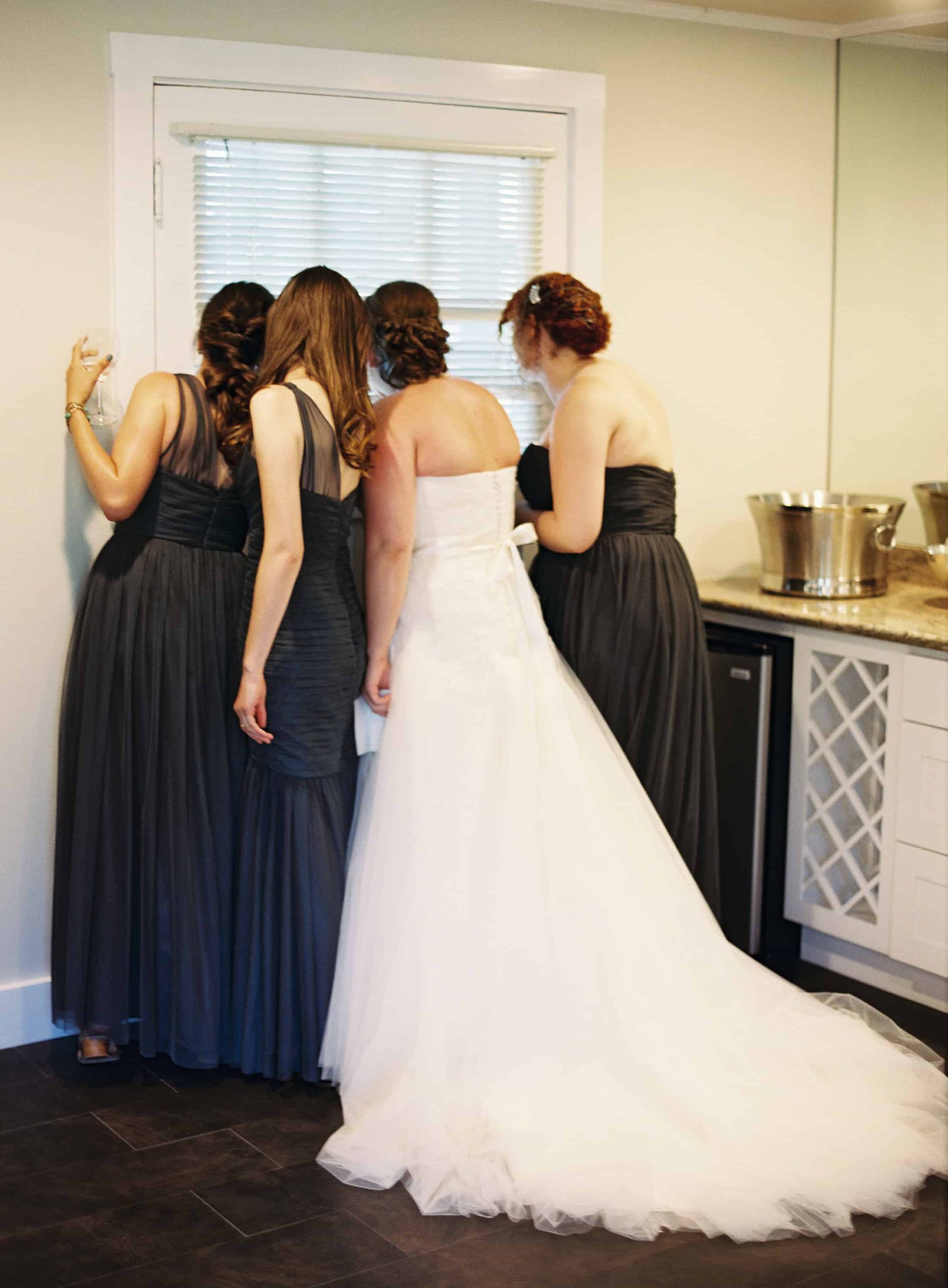 bride and bridesmaids peeking out window