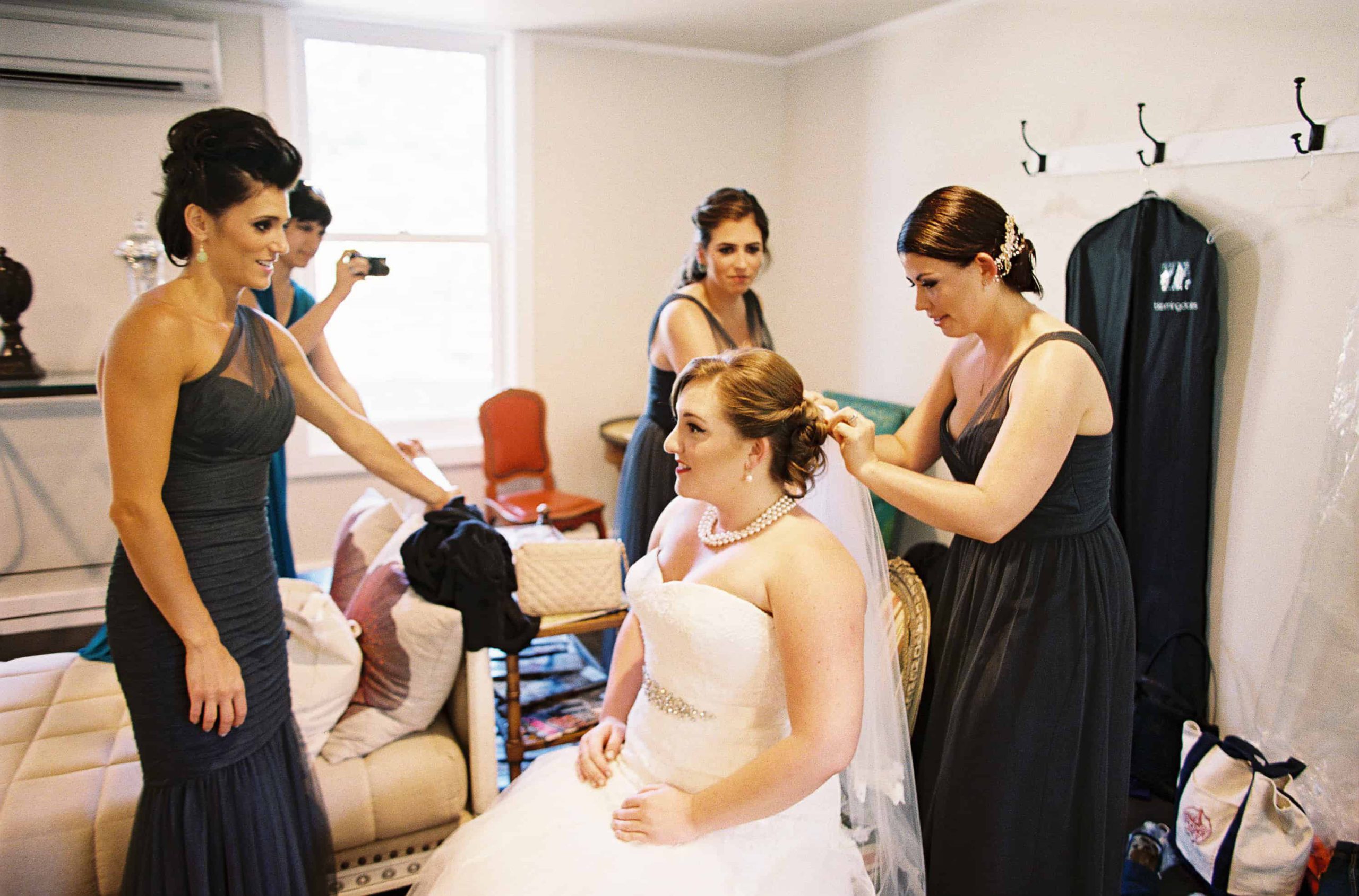 bride and bridesmaids putting veil on