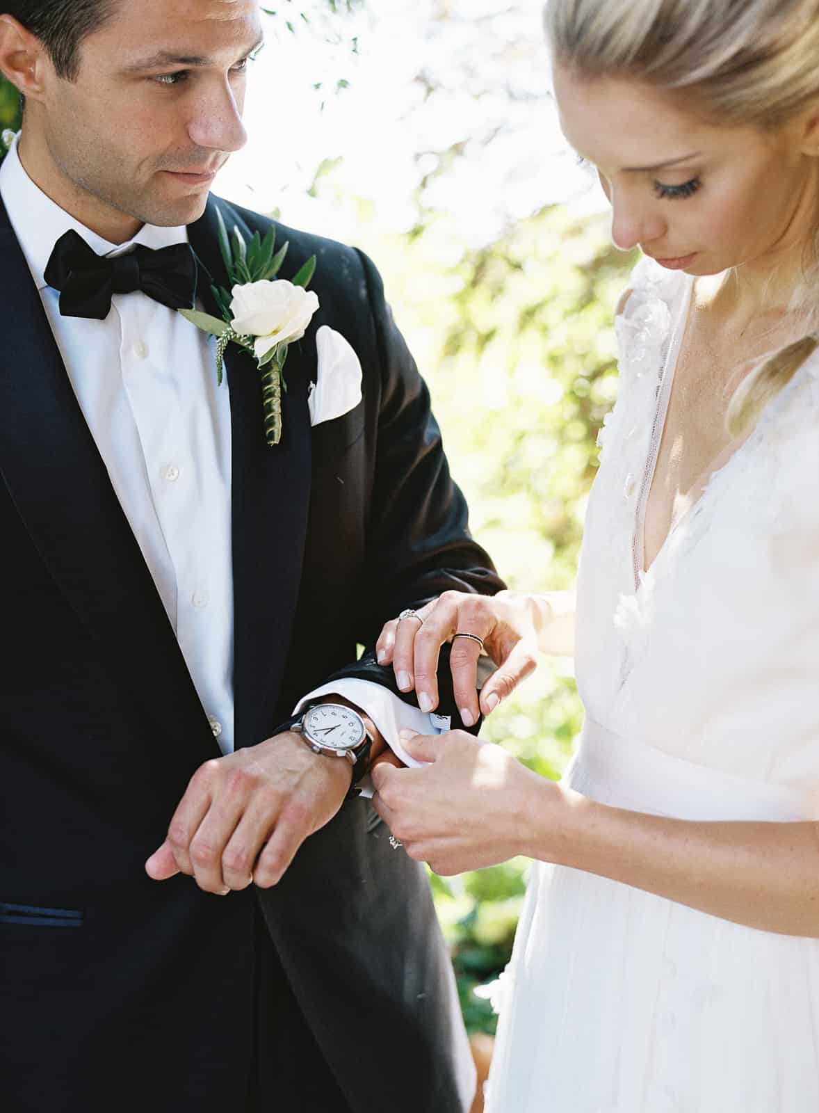 bride helping groom with cufflink