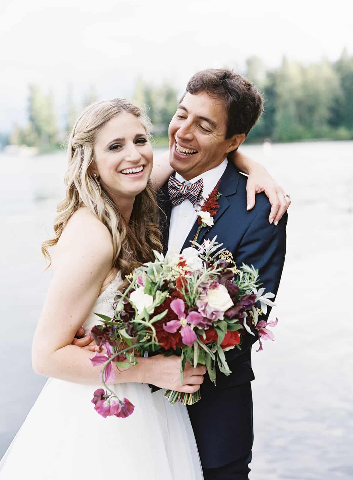 laughing bride and groom with purple bouquet