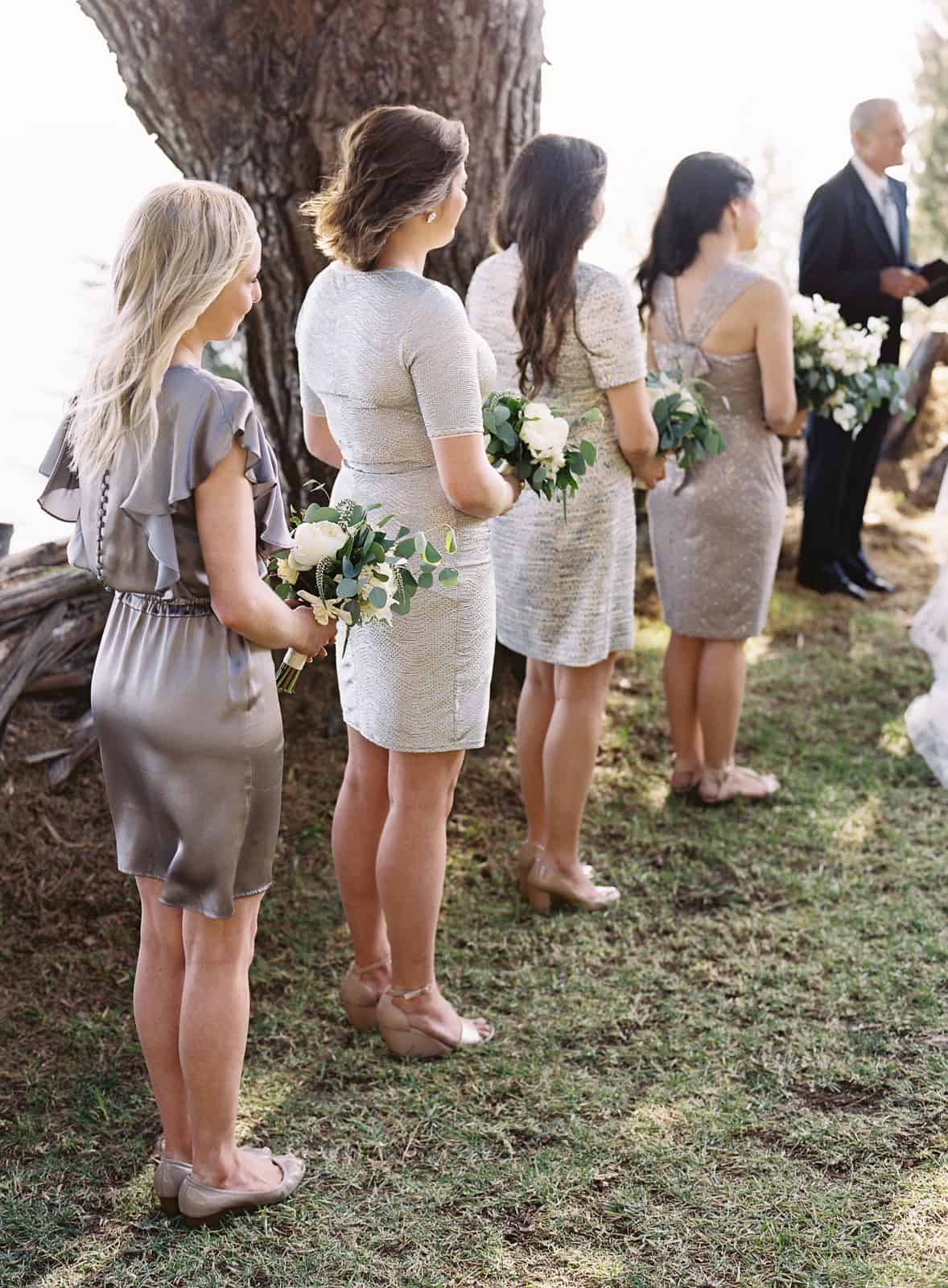 bridesmaids in silver dresses with white and green bouquets lined up