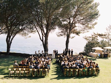 outdoor seaside ceremony with ocean trees and grass lawn
