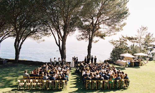 outdoor seaside ceremony with ocean trees and grass lawn