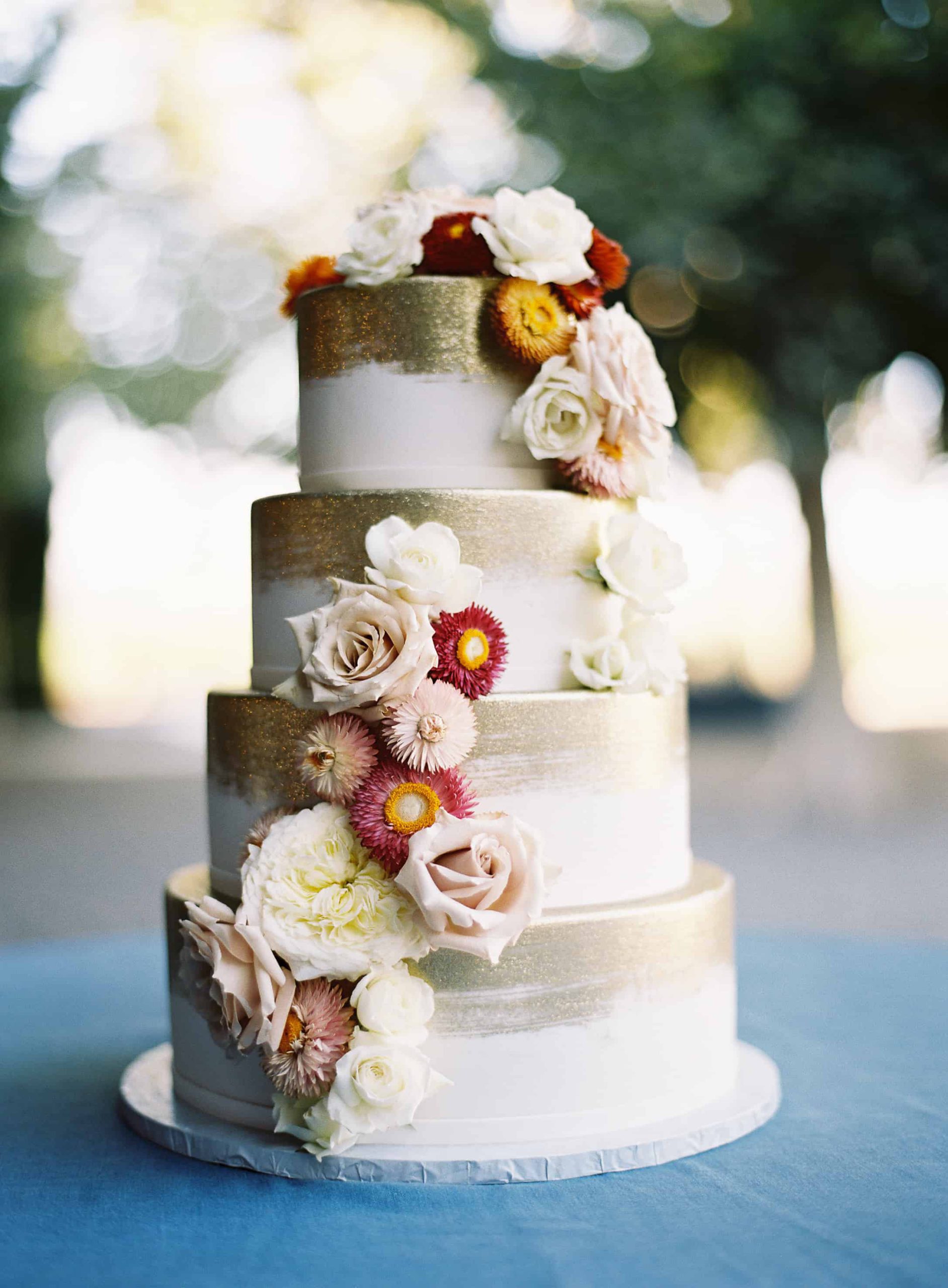 white and gold cake with english daisies and antique white roses