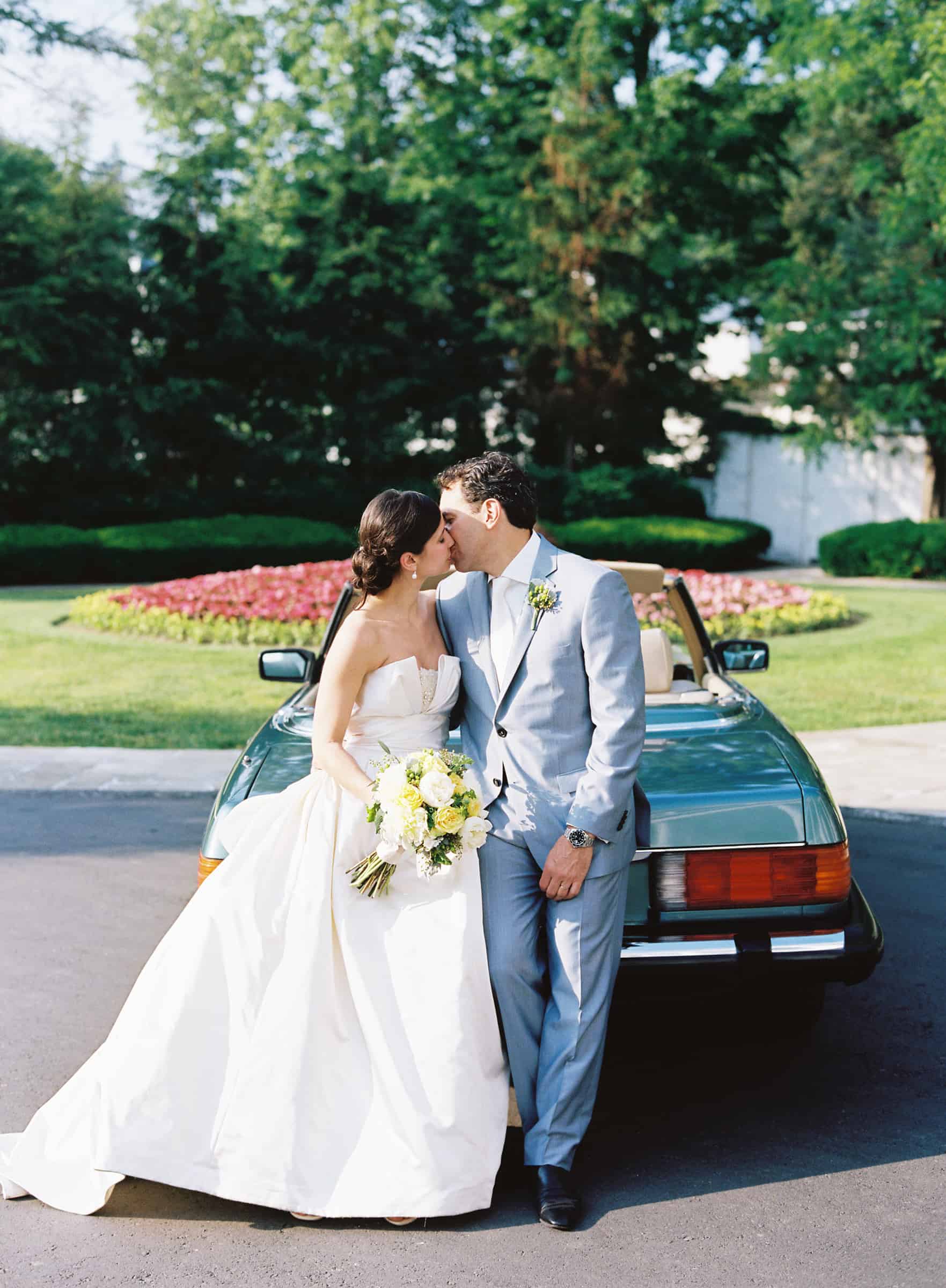 married couple kissing in front of a vintage mercedes-benz 560 SL
