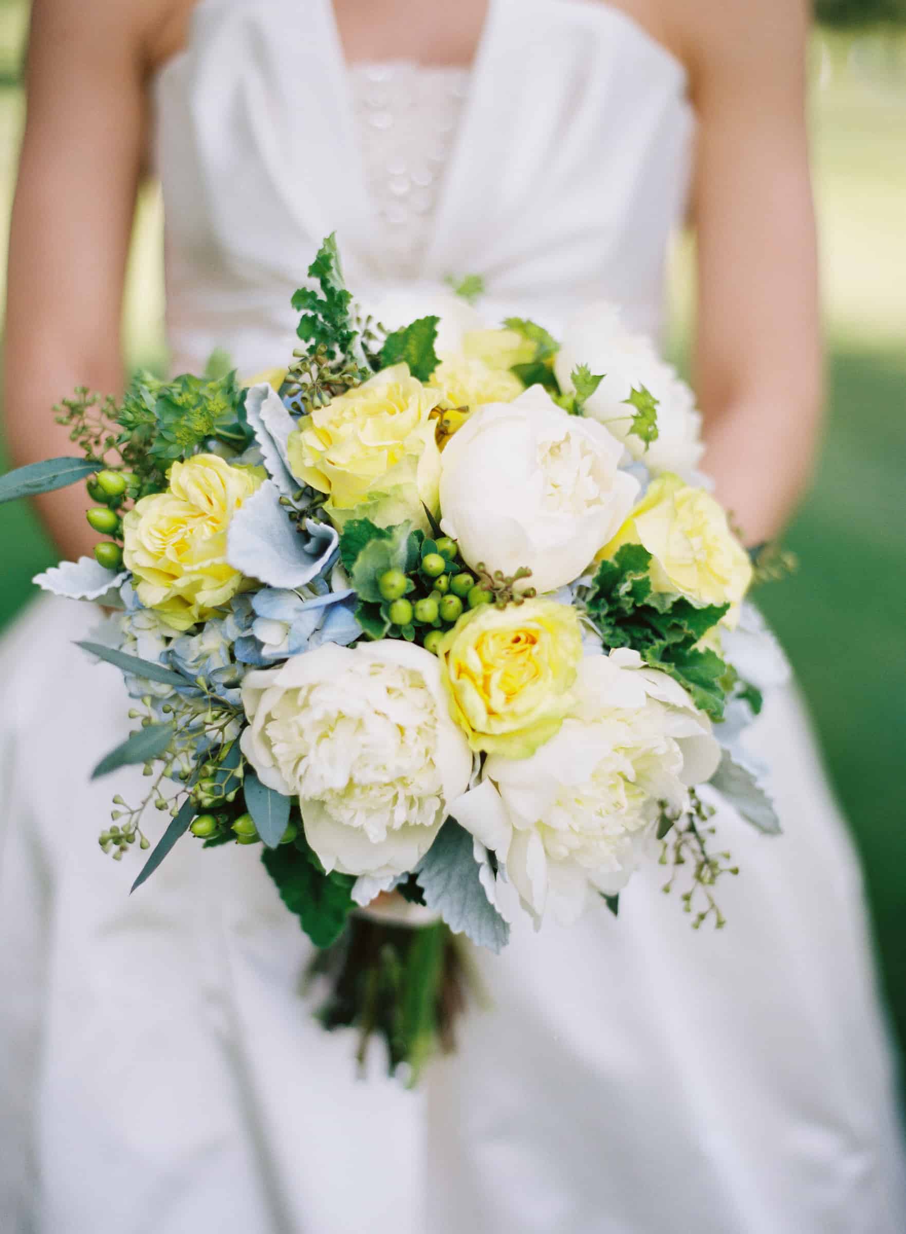 bride holding bouquet with yellow, white and blue flowers
