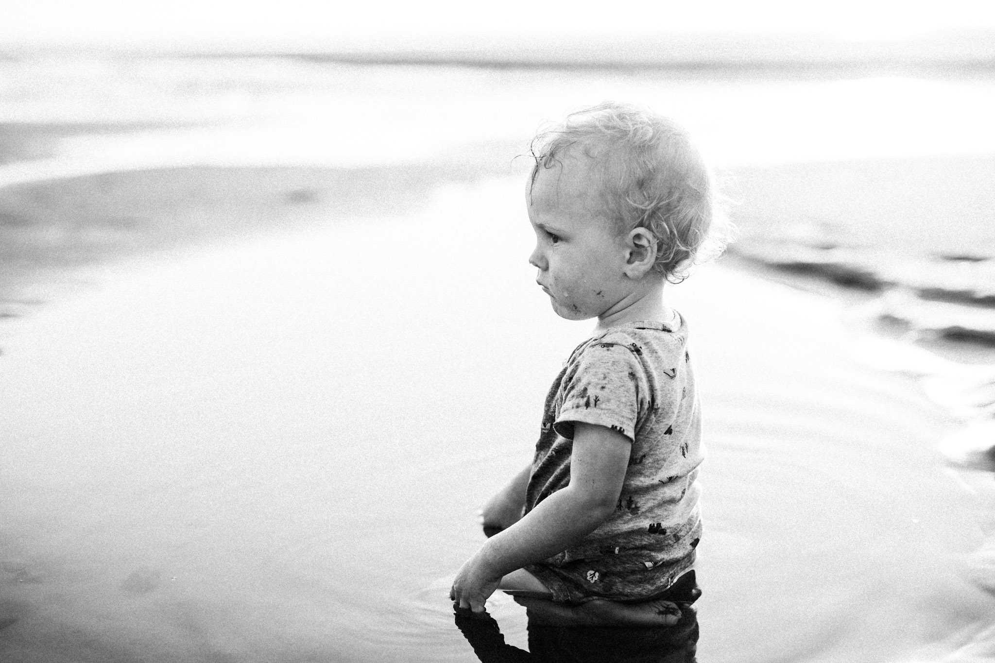 little boy playing in tide pool water at ocean
