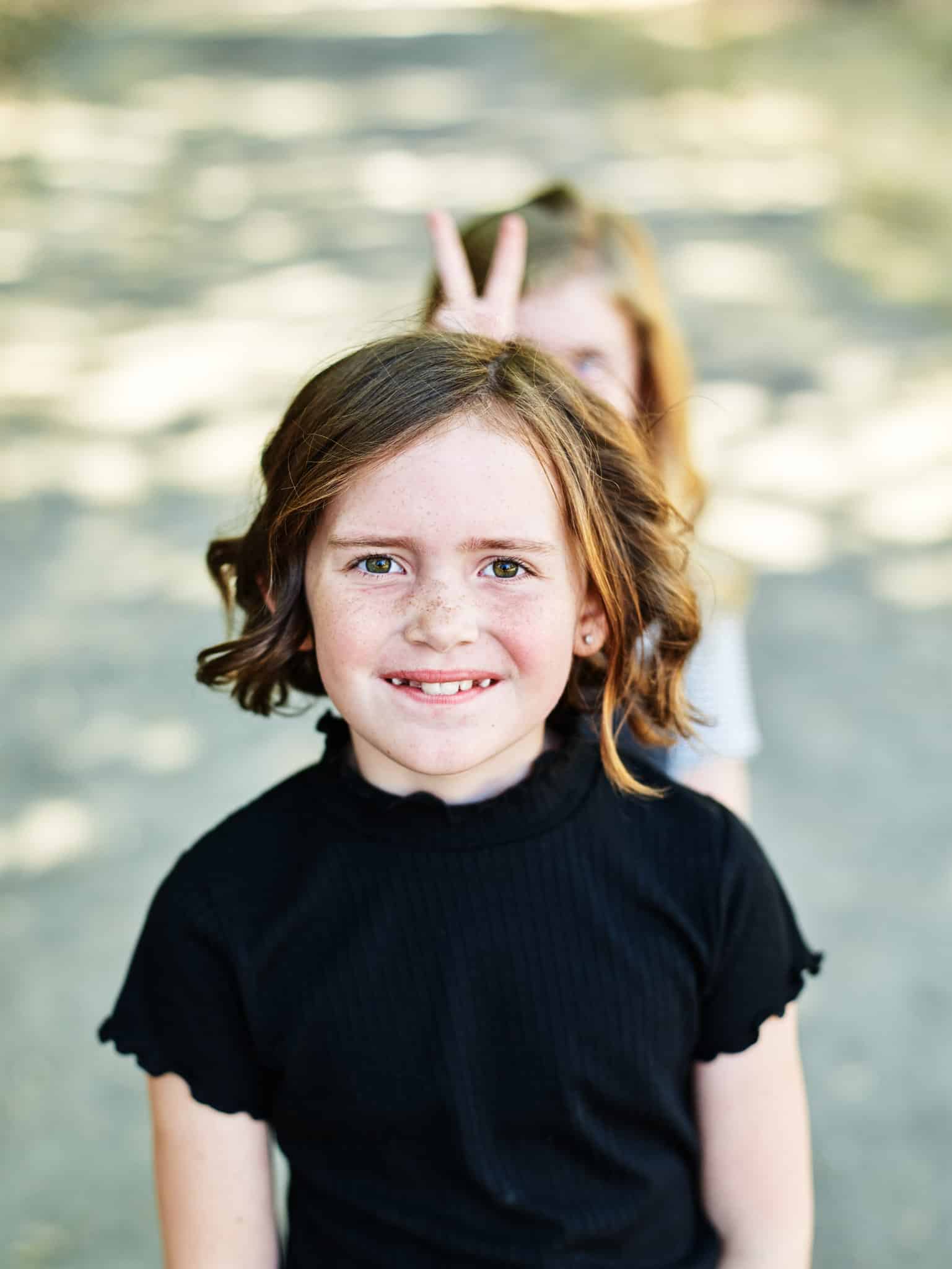 funny photo of girl getting bunny ears from sister